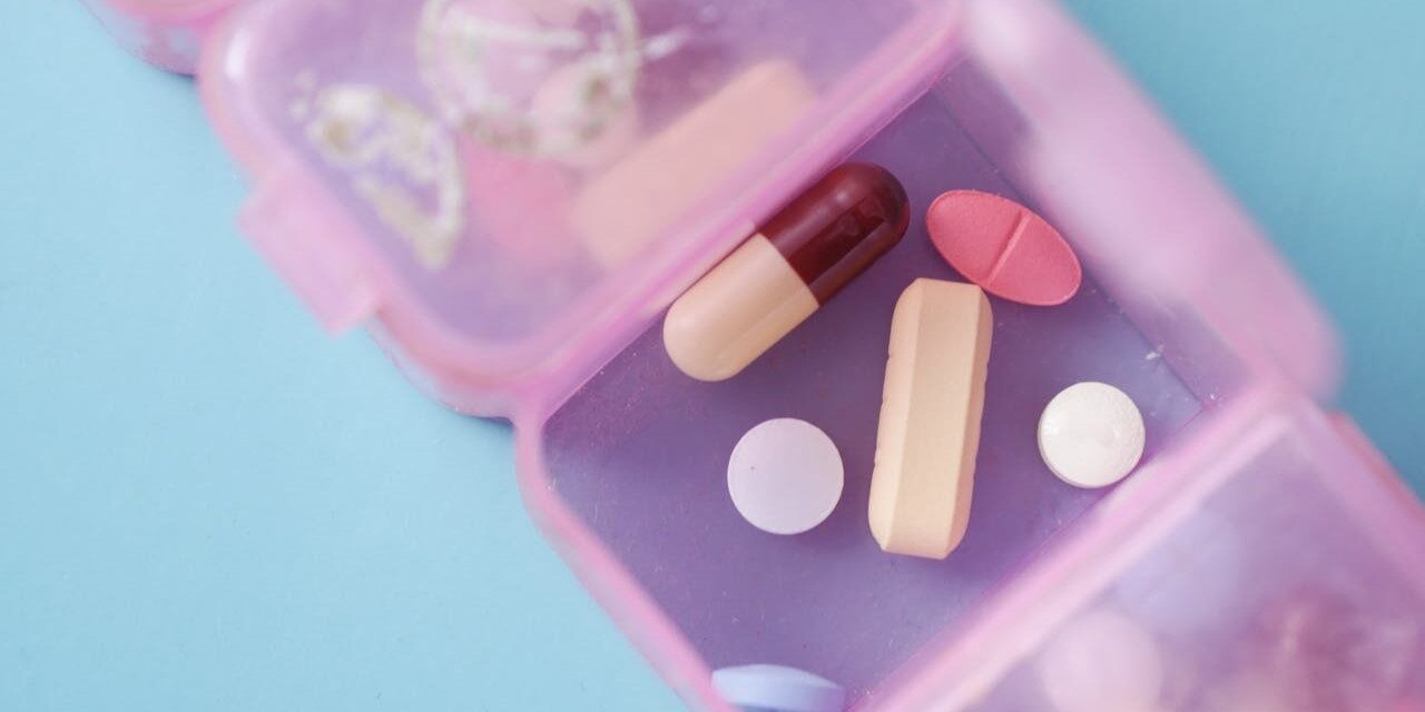 Probiotica supplementen pillendoosje Probiotica supplementen in een roze pillendoosje op een blauwe ondergrond