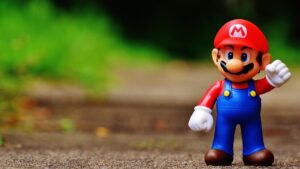 Super Mario speelgoedfiguur in rode pet en blauwe tuinbroek op een buitenpad