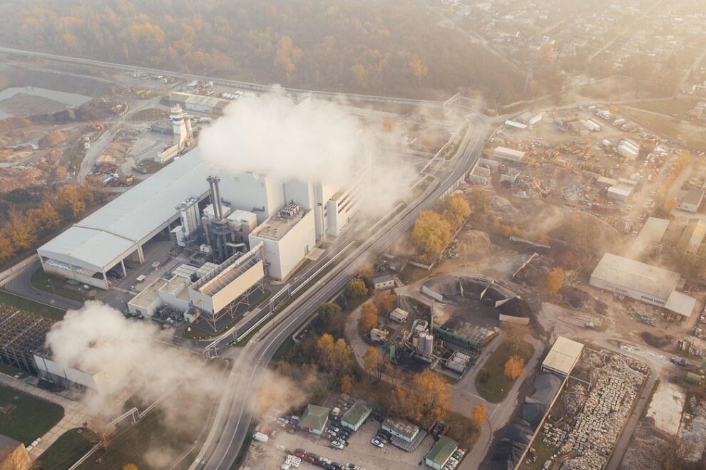 Fabriek met uitstoot op industrieterrein Industrieterrein met rook uitstotende fabriek, symbool voor de noodzaak van zero-emissie logistiek