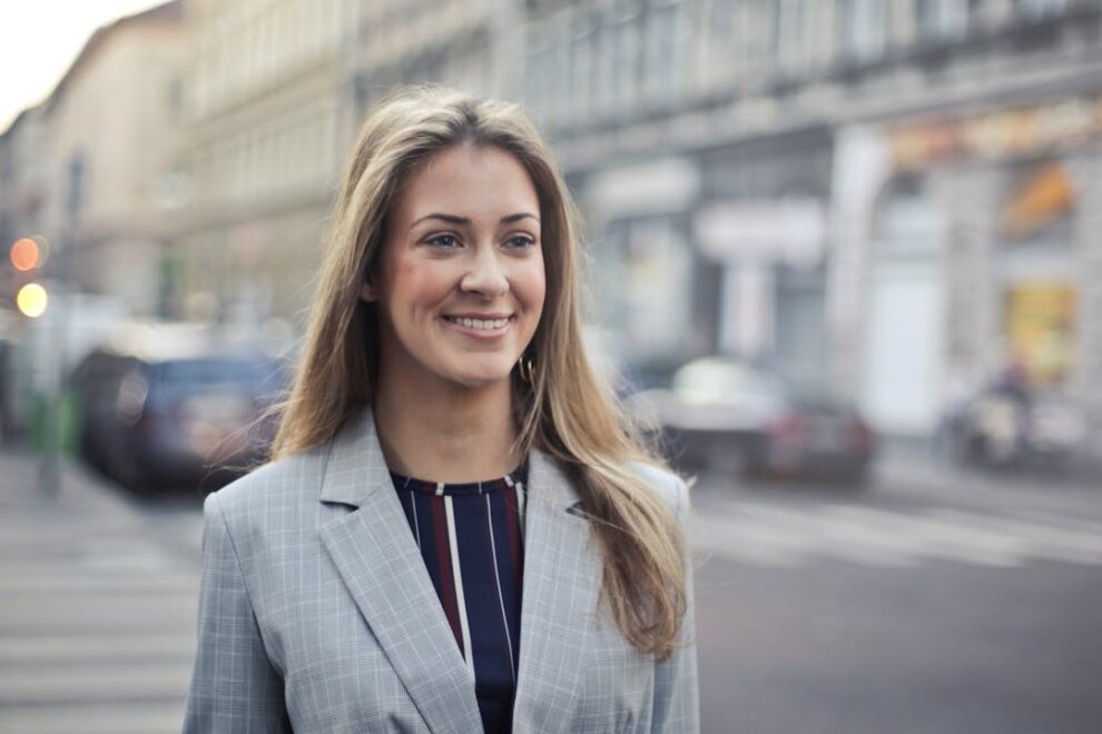 Professionele vrouw in nette blazer tijdens sollicitatieprocedure, lopend door een stedelijke omgeving na een afspraak