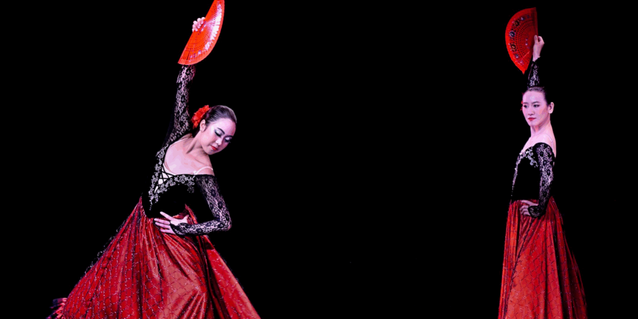 flamenco dansen Twee flamencodansers in rood-zwarte jurken met waaiers op een donker podium