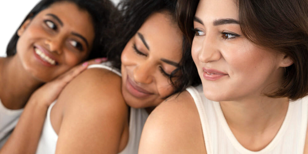 3 vrouwen zitten op een rijtje en leunen tegen elkaar aan
