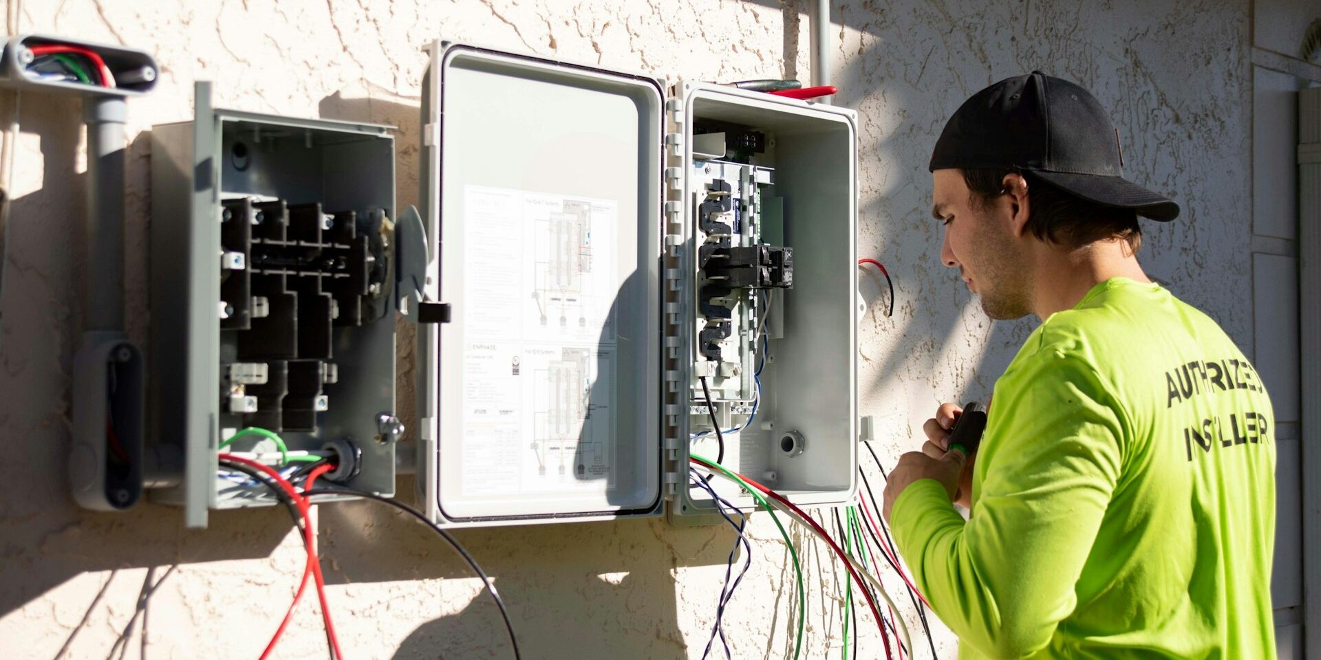 Elektricien installeert verdeelkast buiten aan muur, passend bij beschermingsklasse voor vocht- en weerbestendige apparatuur
