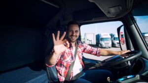 Chauffeur in vrachtwagen toont OK-gebaar tijdens rit volgens rij en rusttijden