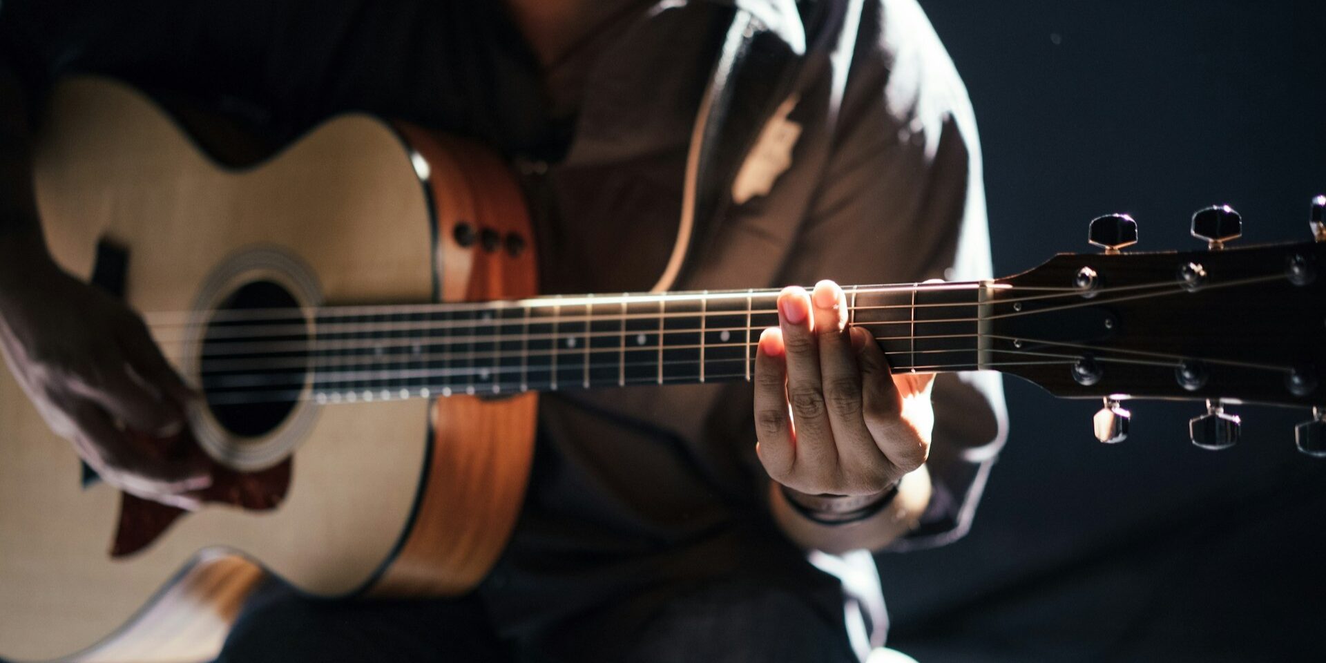 Akoestische gitaar bespeeld met focus op snaren en klankkast bij hoe een gitaar geluid produceert