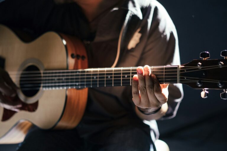 Akoestische gitaar bespeeld met focus op snaren en klankkast bij hoe een gitaar geluid produceert