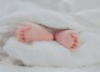 Spanning bij baby’s zichtbaar in ontspannen babyvoetjes onder een zachte witte deken