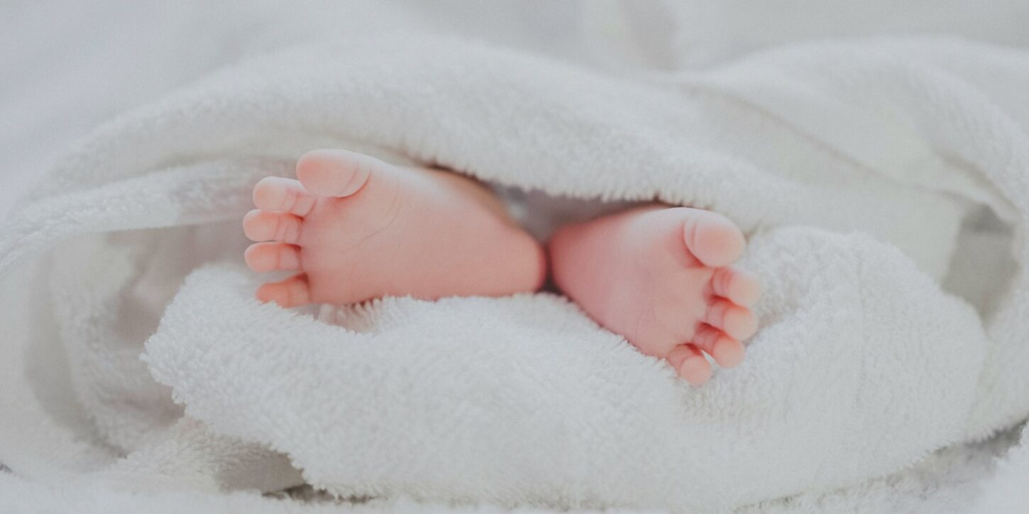 Babyvoetjes onder zachte deken Spanning bij baby’s zichtbaar in ontspannen babyvoetjes onder een zachte witte deken