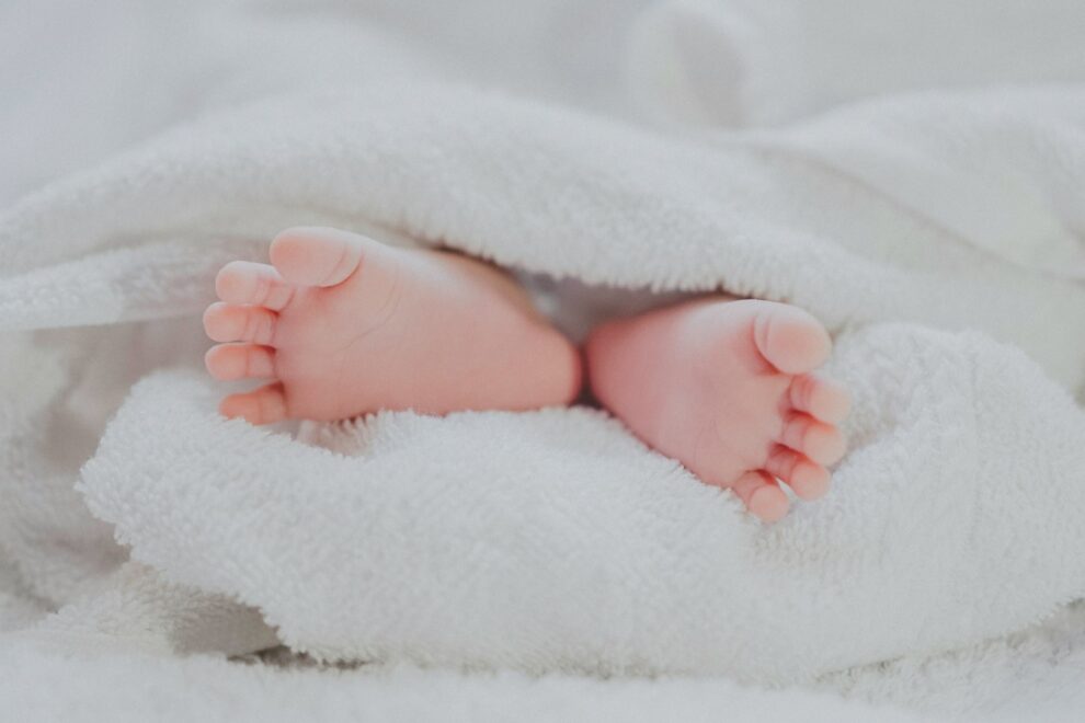 Babyvoetjes onder zachte deken Spanning bij baby’s zichtbaar in ontspannen babyvoetjes onder een zachte witte deken