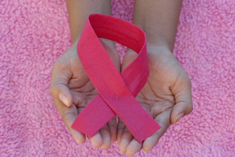 Roze lint symbool voor bewustwording rond kwaadaardige knobbels in handen gehouden