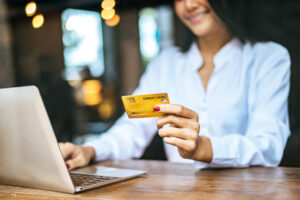 Vrouw gebruikt een creditcard voor een online betaling op haar laptop.