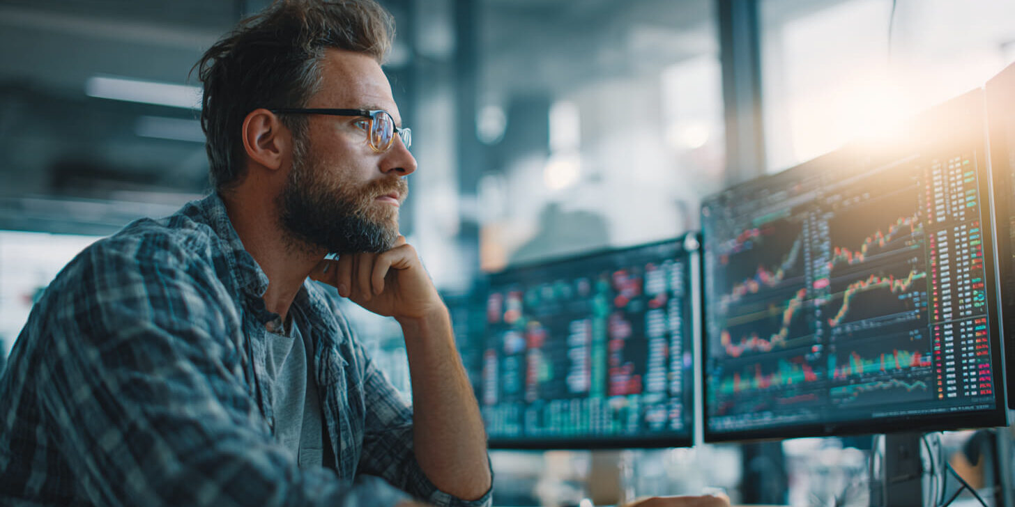 Man in de financien Analist bekijkt koersgegevens op schermen en volgt internationale geldstromen op financiële markten.
