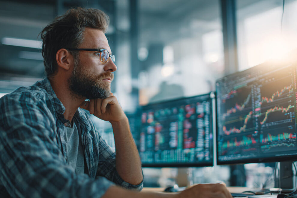 Man in de financien Analist bekijkt koersgegevens op schermen en volgt internationale geldstromen op financiële markten.