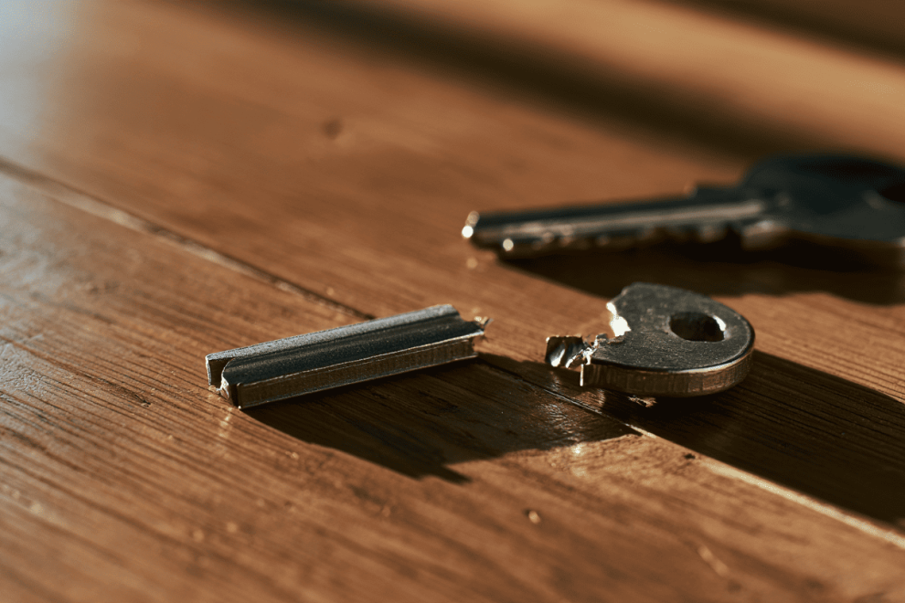 gebroken-huissleutel-in-twee-delen Gebroken huissleutel in twee delen op een houten tafel