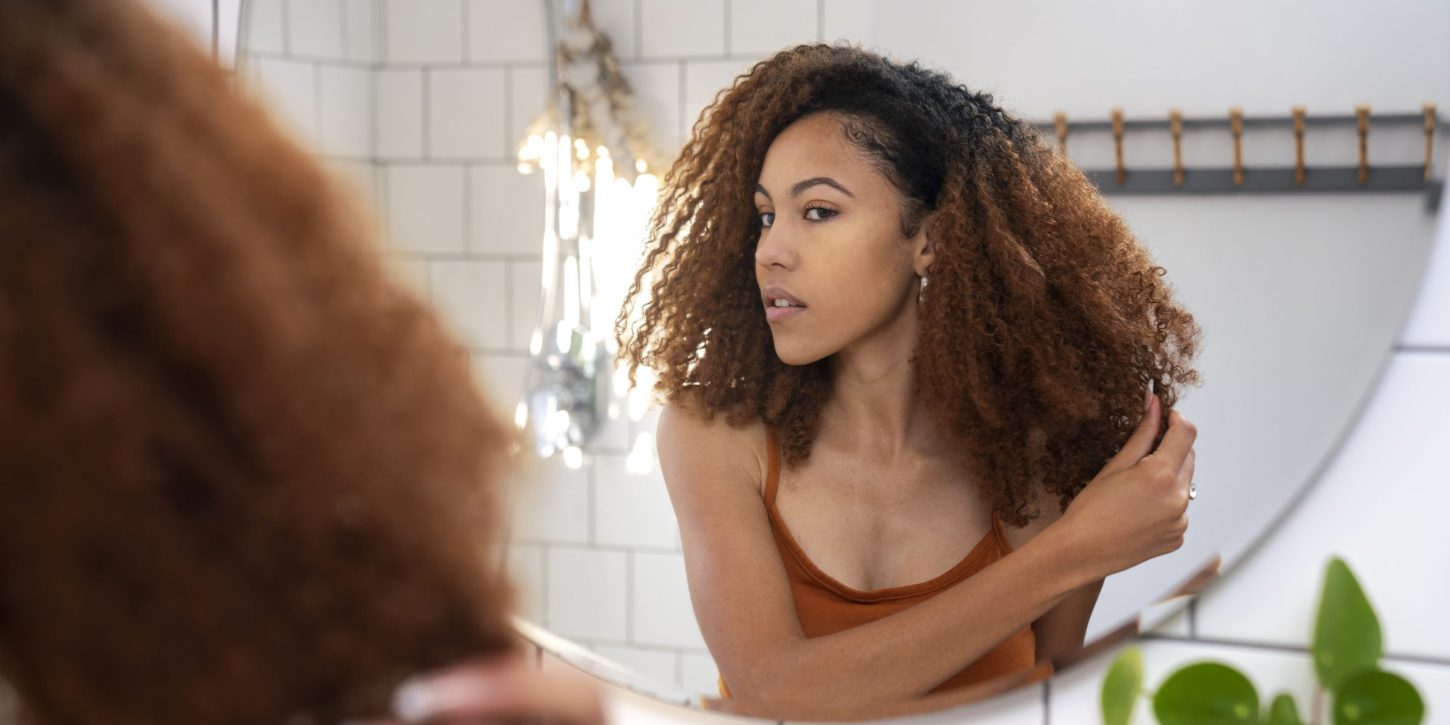 Vrouw met veel krullen Vrouw met veel krullen bekijkt haar haartextuur